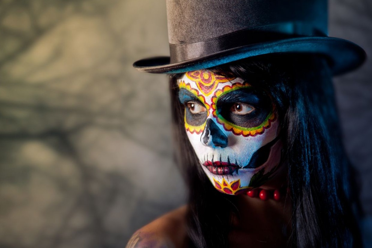 Woman with painted face for Halloween wearing a hat