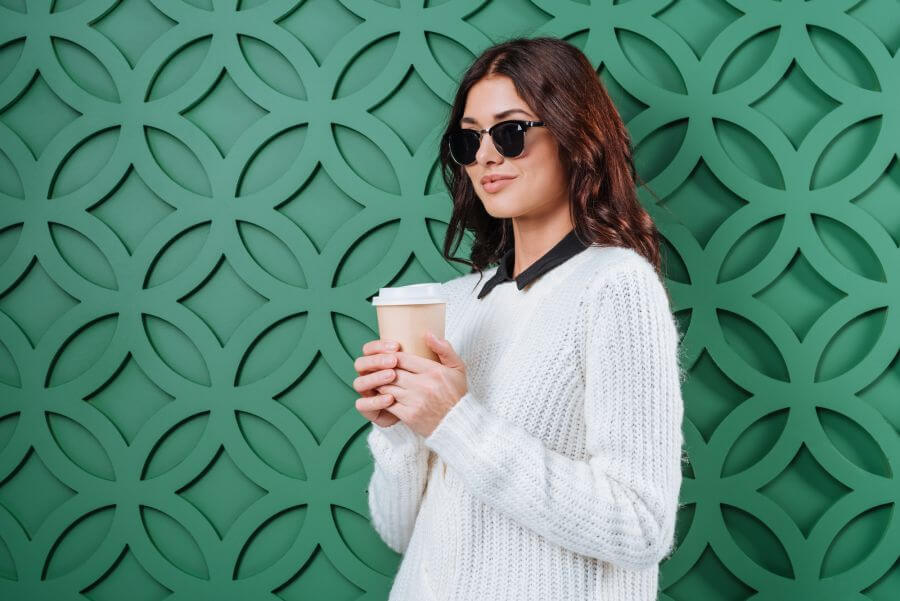 Women wearing a winter sweater and sunglasses holding a coffee paper cup
