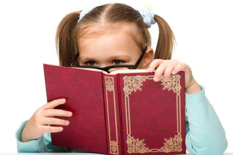 Little girl wearing glasses reading a red cover book